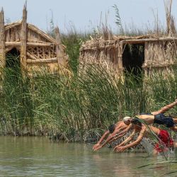 Esta foto muestra a iraquíes saltando al agua cerca de los pantanos de Chibayish, en la provincia meridional iraquí de Dhi Qar. | Foto:Asaad Niazi / AFP