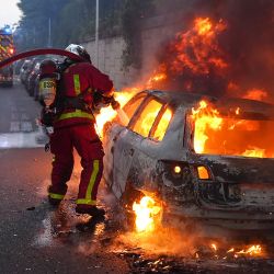 Los bomberos trabajan para apagar un coche en llamas durante una manifestación en Nanterre, al oeste de París, después de que la policía francesa matara a un adolescente que se negó a detenerse en un control de tráfico en la ciudad. El joven de 17 años se encontraba en el suburbio parisino cuando la policía lo mató a tiros después de que infringiera las normas de circulación y no se detuviera, según la fiscalía. El suceso ha suscitado expresiones de conmoción y preguntas sobre la disposición de las fuerzas de seguridad a apretar el gatillo. | Foto:ZAKARIA ABDELKAFI / AFP