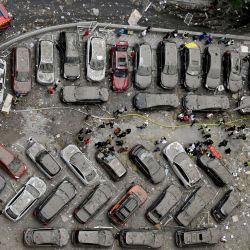 Esta fotografía muestra vehículos destrozados aparcados frente a un edificio de 24 plantas parcialmente destruido como consecuencia del impacto de misiles en la capital ucraniana, Kiev. | Foto:SERGEI SUPINSKY / AFP