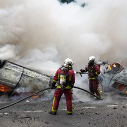 Los bomberos apagan coches en llamas en una calle mientras se producen enfrentamientos al final de una marcha de conmemoración por la muerte de un conductor adolescente por disparos de un policía, en el suburbio parisino de Nanterre, Francia. | Foto:ZAKARIA ABDELKAFI / AFP