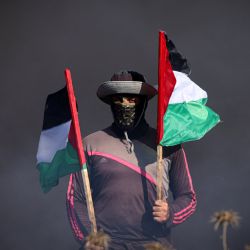Un joven palestino sostiene una bandera junto a neumáticos ardiendo durante una protesta junto a la valla fronteriza con Israel, al este de la ciudad de Gaza. Israel ha intensificado sus operaciones en el norte de Cisjordania, donde se encuentran la ciudad de Yenín y su campo de refugiados adyacente, bastión de grupos armados palestinos en el que se ha producido una oleada de ataques contra israelíes, así como ataques de colonos judíos contra comunidades palestinas. | Foto:MAHMUD HAMS / AFP