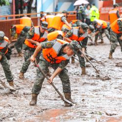 Policías paramilitares despejan una calle tras las inundaciones provocadas por las fuertes lluvias en Chongqing, suroeste de China. | Foto:AFP