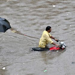 Un motociclista empuja su moto por una calle inundada tras las fuertes lluvias caídas en Lahore, Pakistán. | Foto:ARIF ALI / AFP