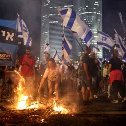 Manifestantes antigubernamentales izan banderas y encienden un pequeño fuego en la autopista Ayalon, en Tel Aviv, tras la dimisión del jefe de policía de Tel Aviv, Ami Ashed. | Foto:OREN ZIV / AFP