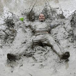 Un campesino cubierto de barro juega en un arrozal durante el "Día Nacional del Arroz", que marca el inicio de la temporada anual de siembra de arroz, en la aldea de Tokha, en las afueras de Katmandú, Nepal. | Foto:PRAKASH MATHEMA / AFP