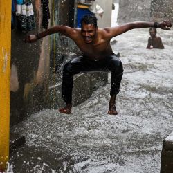 Un hombre disfruta de los chubascos durante las mareas altas cerca del paseo marítimo de Bombay. | Foto:PUNIT PARANJPE / AFP