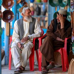 Visitantes afganos sentados frente a tiendas que venden cuencos de arcilla en un mercado del distrito de Istalif, en la provincia noroccidental de Kabul. | Foto:WAKIL KOHSAR / AFP