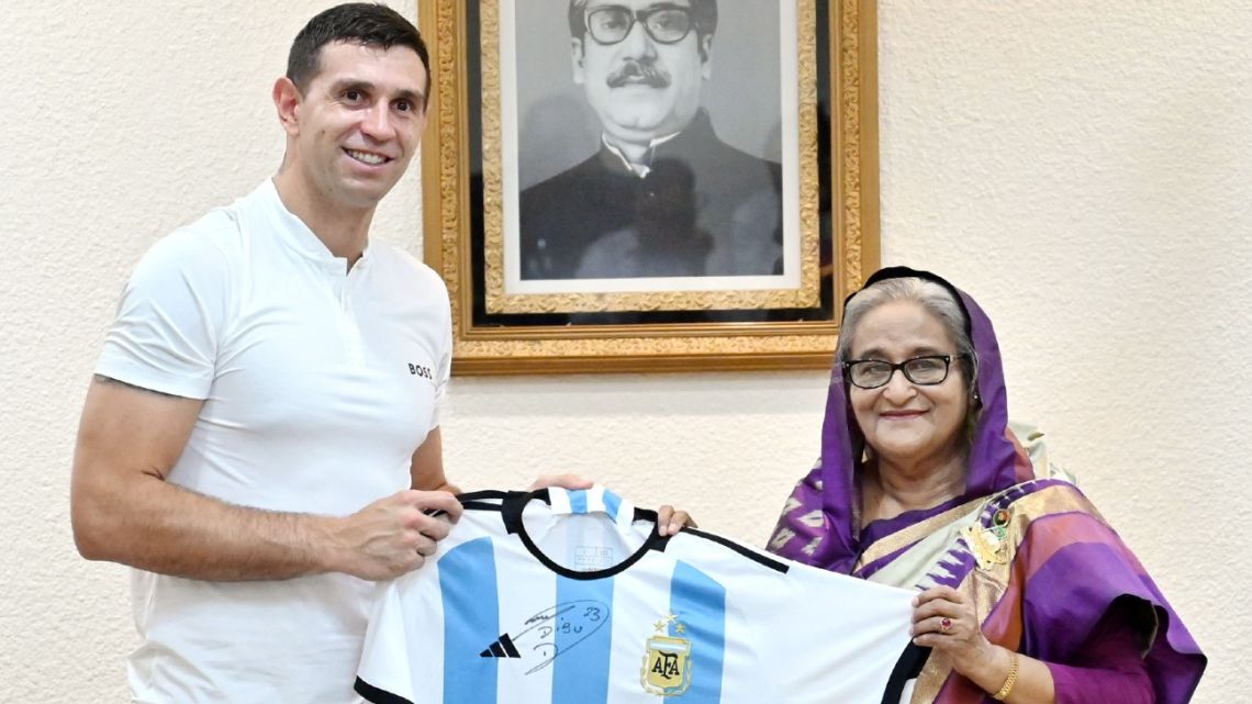 In this handout photo released by Prime Minister's Office of Bangladesh and taken on July 3, 2023, shows Bangladesh's PM Sheikh Hasina (right) posing for a photograph with Argentina's football team goalkeeper Emiliano Martínez (left) in Dhaka. 