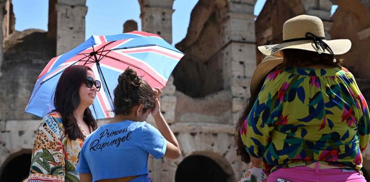 Los turistas se protegen del sol con sombrillas cerca del Coliseo en Roma, cuando Italia se ve afectada por una ola de calor. Foto de Alberto PIZZOLI / AFP