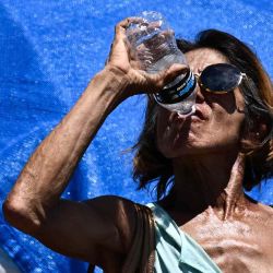 Una persona bebe una botella de agua mientras camina en "The Zone", un vasto campamento para personas sin hogar, durante una ola de calor récord en Phoenix, Arizona. Foto Patrick T. Fallon / AFP | Foto:AFP
