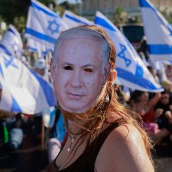 Un manifestante con una máscara que representa al primer ministro israelí Benjamin Netanyahu participa en una sentada para bloquear la entrada de la Knesset, el parlamento de Israel, en Jerusalén, en medio de una ola de protestas de meses contra la reforma judicial planificada por el gobierno. | Foto:MENAHEM KAHANA / AFP