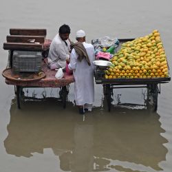 Vendedores de frutas esperan en medio de una calle inundada en Karachi, Pakistán. | Foto:RIZWAN TABASSUM / AFP