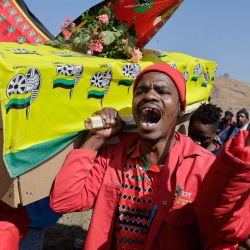 Simpatizantes de los Combatientes por la Libertad Económica (EFF) portan un ataúd simulado cubierto con una bandera del Congreso Nacional Africano (ANC) en el mitin de cumpleaños del EFF, que celebra el 10º aniversario del partido, en Marikana. | Foto:GUILLEM SARTORIO / AFP