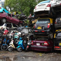 Un peatón pasa junto a vehículos confiscados e incautados apilados al borde de una carretera durante las lluvias en Mumbai, India. | Foto:INDRANIL MUKHERJEE / AFP