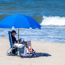 El presidente estadounidense Joe Biden y la primera dama Jill Biden sentados bajo una sombrilla en Rehoboth Beach, Delaware. | Foto:JIM WATSON / AFP