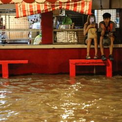 La gente espera el transporte a lo largo de una calle inundada de Manila mientras la tormenta tropical Khanun intensifica la lluvia del monzón del suroeste. | Foto:Earvin Perias / AFP
