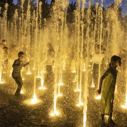 Niños judíos ultraortodoxos junto con otros jóvenes se refrescan durante el calor del verano, en una fuente de agua en Jerusalén. | Foto:MENAHEM KAHANA / AFP