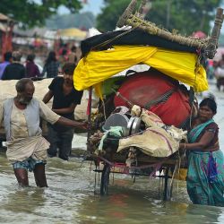 Varias personas con sus pertenencias vadean el agua de las inundaciones a orillas del río Ganges, en Prayagraj, tras la subida del nivel de los ríos Ganges y Yamuna como consecuencia de las lluvias. | Foto:SANJAY KANOJIA / AFP