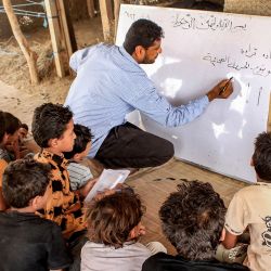 Mohammed Awaji, un profesor voluntario, imparte una clase de árabe a los niños de una escuela construida con paja por los lugareños en un campamento para desplazados por el conflicto de Abs, en la provincia septentrional yemení de Hajjah. | Foto:ESSA AHMED / AFP