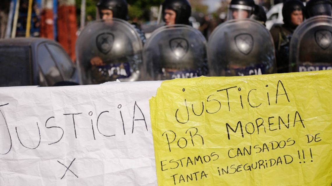 A banner that reads 'Justice for Morena, we are tired of so much insecurity' is seen as policemen stand guard during a demonstration held by residents of the Lanus municipality demanding justice for the crime of an 11-year-old girl to steal her backpack in Lanús, Buenos Aires Province, on August 9, 2023.