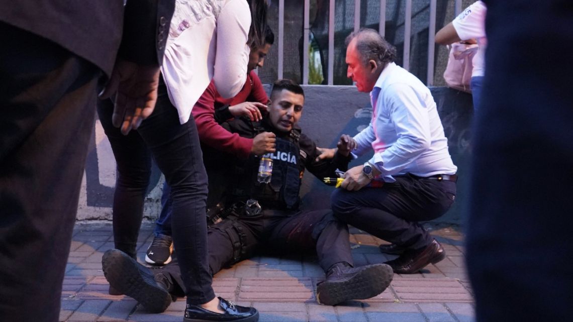 A policeman is assisted after being wounded after shots were fired at the end of a rally of Ecuadorean presidential cadidate Fernando Villavicencio in Quito, on August 9, 2023. 