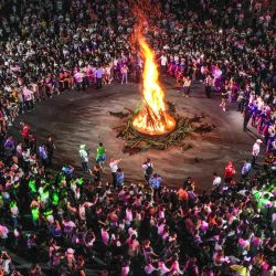 Esta foto muestra a personas reunidas alrededor de una fogata mientras celebran el festival de la antorcha en el condado de Qinglong, suroeste de China. | Foto:AFP