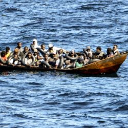 Migrantes de origen africano que intentan huir a Europa están hacinados a bordo de un bote pequeño, mientras los guardacostas tunecinos se preparan para transferirlos a su embarcación, en el mar entre Túnez e Italia. | Foto:FETHI BELAID / AFP
