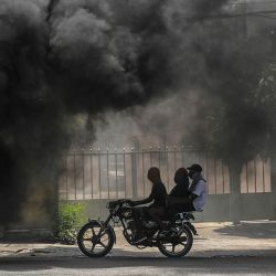 Una motocicleta circula junto al humo de los neumáticos quemados durante una manifestación contra la inseguridad en Puerto Príncipe, Haití. | Foto:Richard Pierrin / AFP