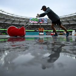 Un miembro del personal de tierra usa un rodillo de escobilla de goma para secar las pistas después de las fuertes lluvias dentro del estadio el día inaugural del Campeonato Mundial de Atletismo en el Centro Nacional de Atletismo en Budapest. | Foto:KIRILL KUDRYAVTSEV / AFP