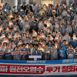 Los principales miembros del Partido Demócrata de la oposición de Corea del Sur sostienen velas eléctricas y carteles que dicen "¡Retirar el vertido de agua contaminada de Fukushima!" durante una manifestación contra el plan de Japón de liberar agua tratada de la planta nuclear de Fukushima, en la Asamblea Nacional en Seúl. | Foto:JUNG YEON-JE / AFP