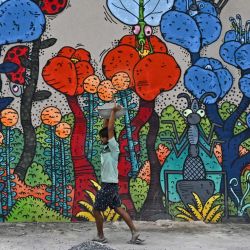 Un trabajador pasa junto a un mural en Nueva Delhi, India. | Foto:ARUN SANKAR / AFP