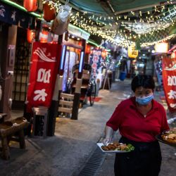 Esta fotografía muestra a una mujer llevando comida a los clientes en un restaurante japonés en Hong Kong. | Foto:ISAAC LAWRENCE / AFP