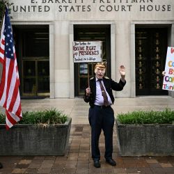 Un manifestante disfrazado a semejanza del ex presidente estadounidense Donald Trump sostiene un cartel frente al juzgado estadounidense E. Barrett Prettyman en Washington, DC. | Foto:Brendan Smialowski / AFP