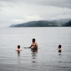 La gente nada en la playa de Dores en el lago Ness en Escocia. | Foto:Andy Buchanan / AFP