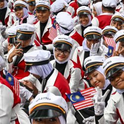 Los voluntarios esperan antes de participar en las celebraciones del 66º Día Nacional en Putrajaya, la capital administrativa de Malasia. El país conmemora la independencia de la Federación de Malaya del dominio británico en 1957. | Foto:MOHD RASFAN / AFP
