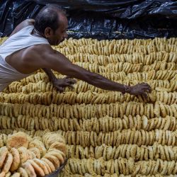Un trabajador de una pastelería prepara un dulce tradicional conocido localmente como "Khaja", que se vende popularmente antes del festival hindú de "Nag Panchami", en Ahmedabad, India. | Foto:SAM PANTHAKY / AFP