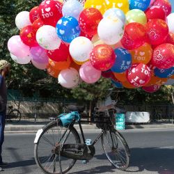 Un vendedor de globos afgano deja a un lado su bicicleta mientras espera a los clientes en una calle de Kabul. | Foto:WAKIL KOHSAR / AFP