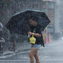 Una mujer camina con un paraguas durante las fuertes lluvias cerca del puerto de Su-ao, en Yilan, mientras el tifón Haikui toca tierra en el este de Taiwán. | Foto:Hwa Cheng / AFP
