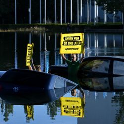 Activistas de Greenpeace se encuentran en un estanque con autos viejos y sostienen pancartas cerca de la entrada del Salón Internacional del Automóvil celebrado en Munich, sur de Alemania. | Foto:Christof Stache / AFP