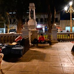 A couple dances tango at the outdoor 'A la Gorra' milonga, as a homeless man lounging on his mattress looks on, at Plaza del Congreso in Buenos Aires, Argentina, on August 31, 2023. 