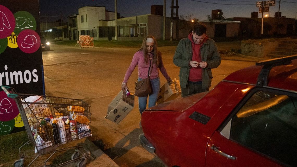 An Uruguayan couple carries their groceries to their car in Concordia, Entre Ríos Province, on August 28, 2023. 