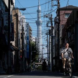 Un hombre pasa en bicicleta por edificios antiguos mientras se muestra detrás el Tokyo Skytree, uno de los edificios más altos del mundo.Minowa de Taito Ward en Tokio. Foto de Richard A. Brooks / AFP  | Foto:AFP