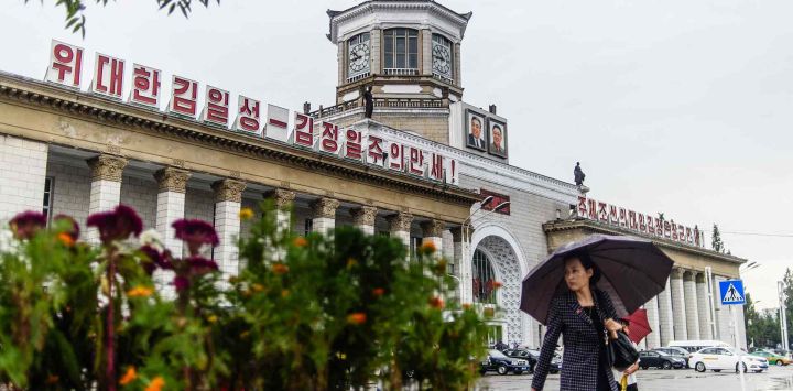 Una mujer usa su paraguas bajo la lluvia mientras camina afuera de la estación de tren de Pyongyang. Foto de KIM Won Jin / AFP