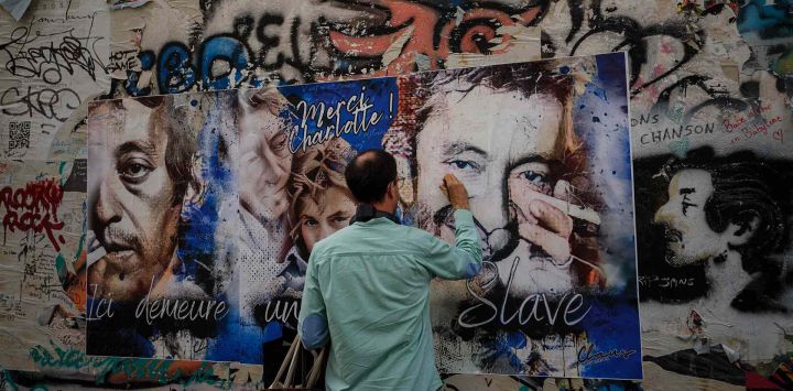 Un visitante escribe en un cartel colocado en la pared frente a la "Maison Gainsbourg", en París. Foto de Dimitar DILKOFF / AFP