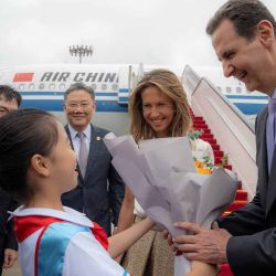 El presidente de Siria, Bashar al-Assad, y a la primera dama, Asma al-Assad, siendo recibidos a su llegada al aeropuerto de Beijing. Foto de SANA / AFP | Foto:AFP