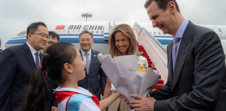 El presidente de Siria, Bashar al-Assad, y a la primera dama, Asma al-Assad, siendo recibidos a su llegada al aeropuerto de Beijing. Foto de SANA / AFP