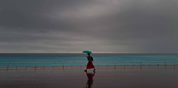 Una mujer se protege de las fuertes lluvias con un paraguas mientras camina por el "Promenade des Anglais" en la ciudad de Niza, en la Riviera francesa. Foto de Valery HACHE / AFP 