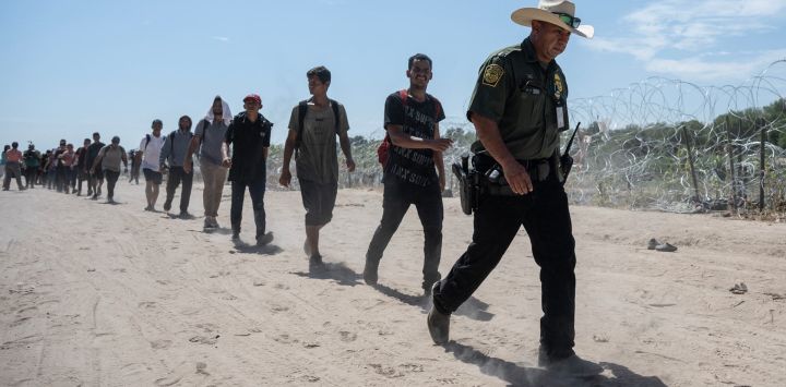Migrantes de Venezuela caminan detrás de un agente de la Patrulla Fronteriza de EE. UU. hacia un área de procesamiento después de cruzar el Río Grande en Eagle Pass, Texas. Docenas de migrantes llegaron a la frontera entre Estados Unidos y México con la esperanza de que se les permitiera ingresar. Estados Unidos, donde las fuerzas fronterizas estadounidenses informaron de 1,8 millones de encuentros con migrantes en los últimos 12 meses.