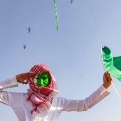 Un hombre que lleva una mascarilla pintada con los colores verde y blanco de Arabia Saudita saluda mientras asiste a un espectáculo aéreo que conmemora las celebraciones del 93º Día Nacional de Arabia Saudita en Riad. | Foto:Fayez Nureldine / AFP