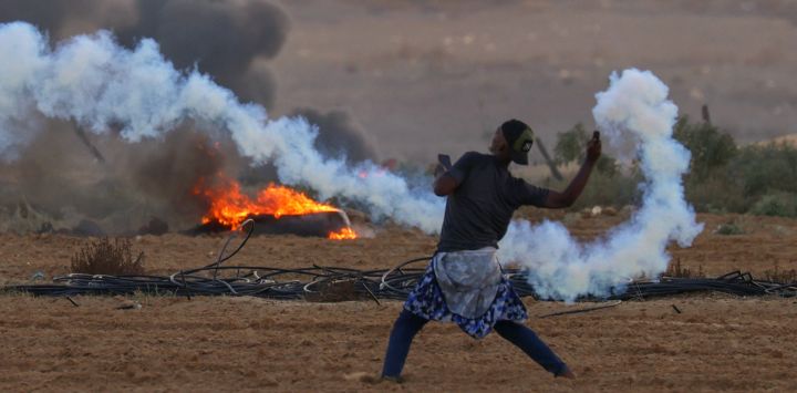 Un manifestante palestino devuelve un bote de gas lacrimógeno durante enfrentamientos con soldados israelíes al este de Rafah, en el sur de la Franja de Gaza, cerca de la valla fronteriza entre Israel y Gaza.